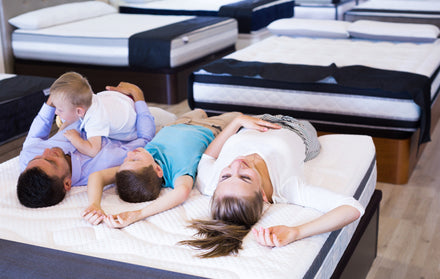 Family testing a mattress in a mattress store.
