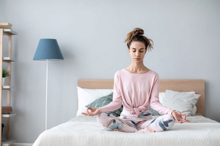 A young woman meditating on the bed.