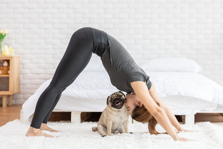Woman practicing yoga with her puppy.