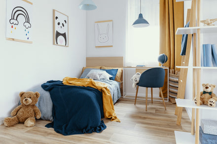 Bedroom with a twin bed, desk and chair, decorated in navy blue and mustard.