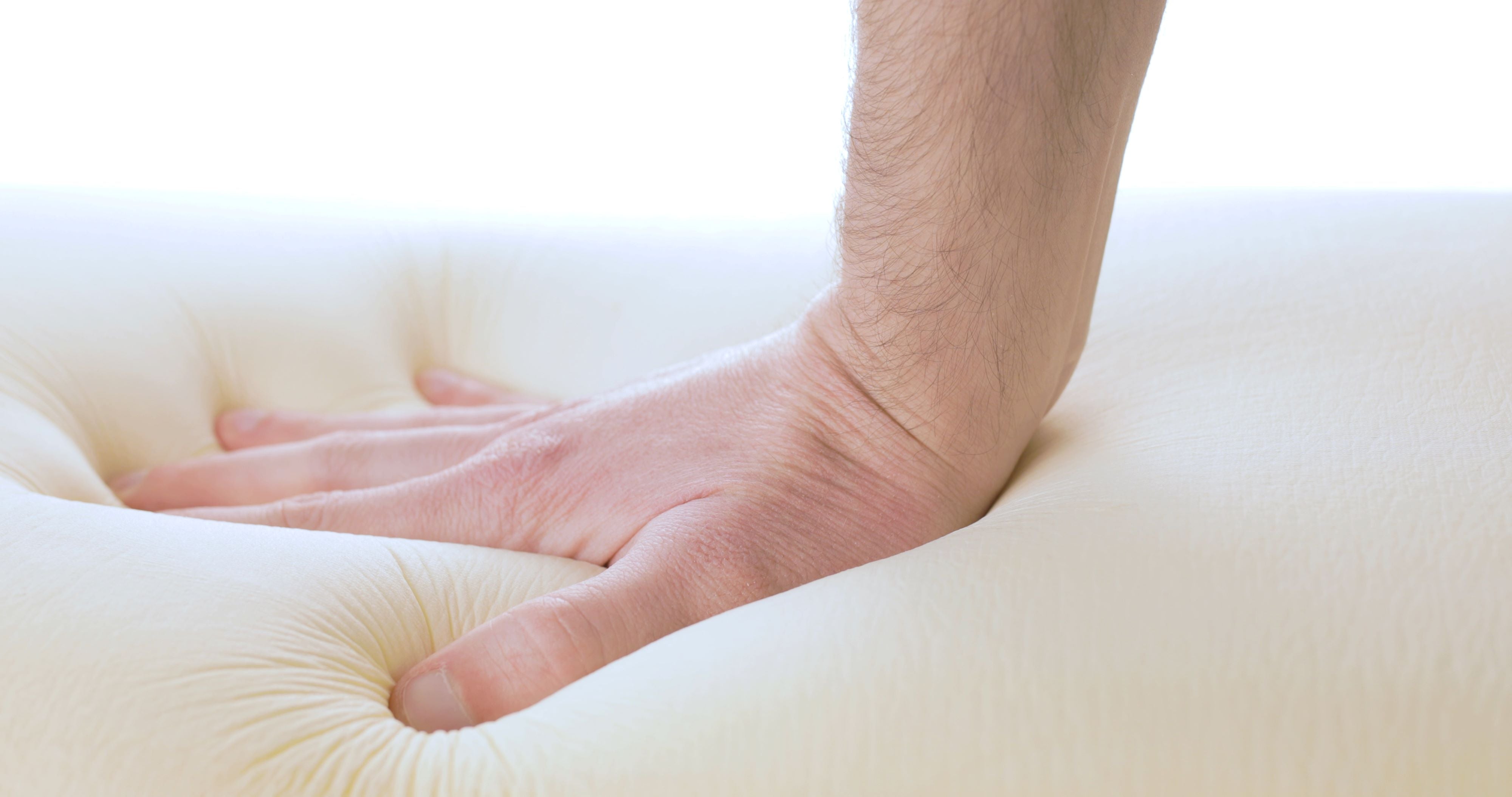 Someone is trying out a memory foam mattress by putting his palm into the soft material.