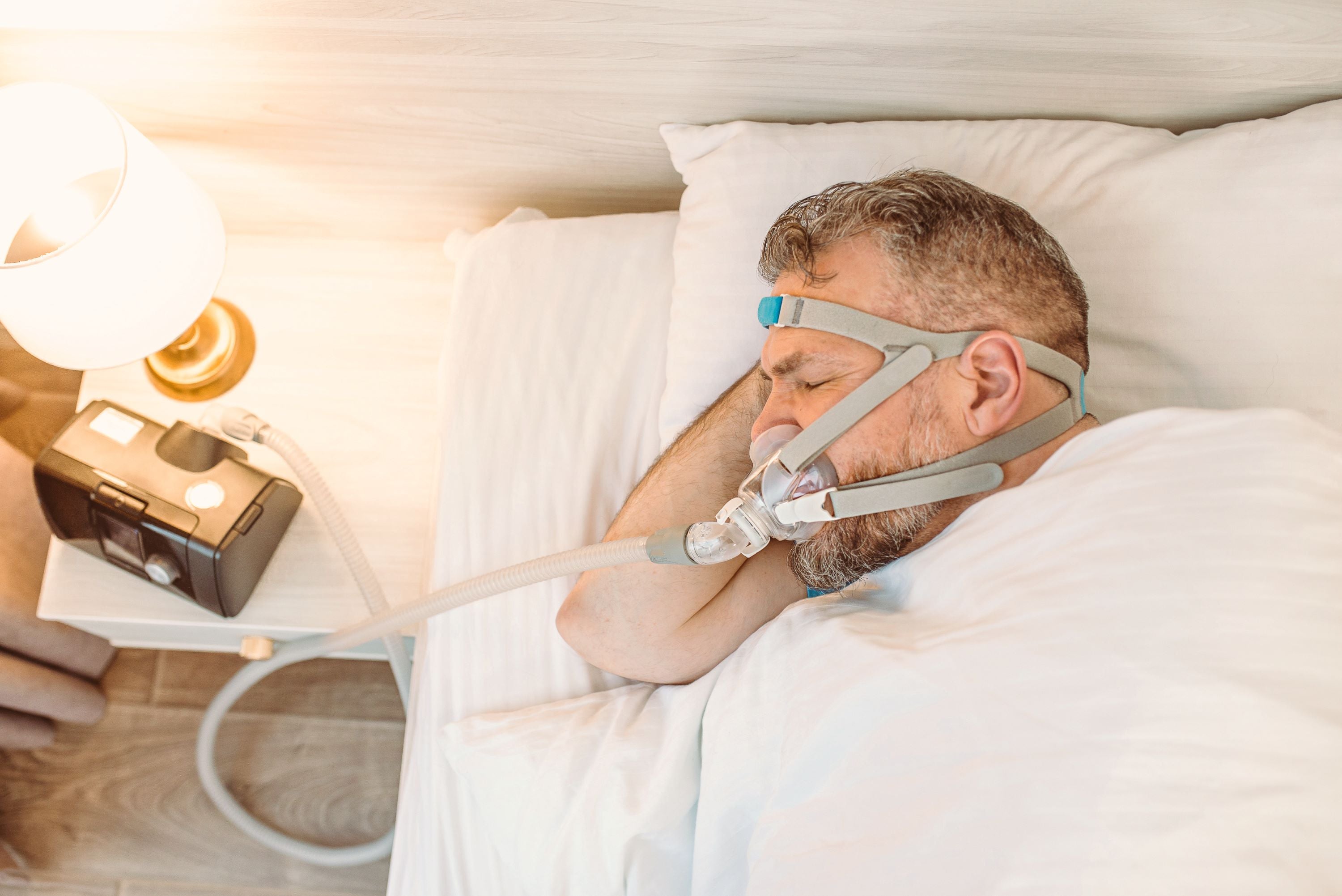 Sleeping man with chronic breathing issues considers using CPAP machine in bed