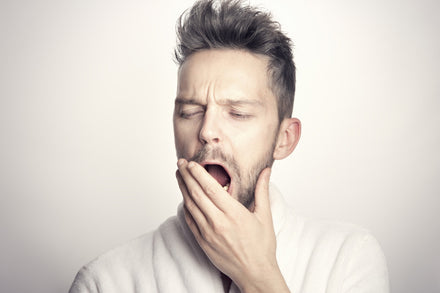 Tired man yawning, covering his mouth with his hand