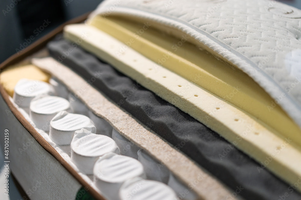 Open hybrid mattress showing the pocketed coils and several support and comfort layers of foam.