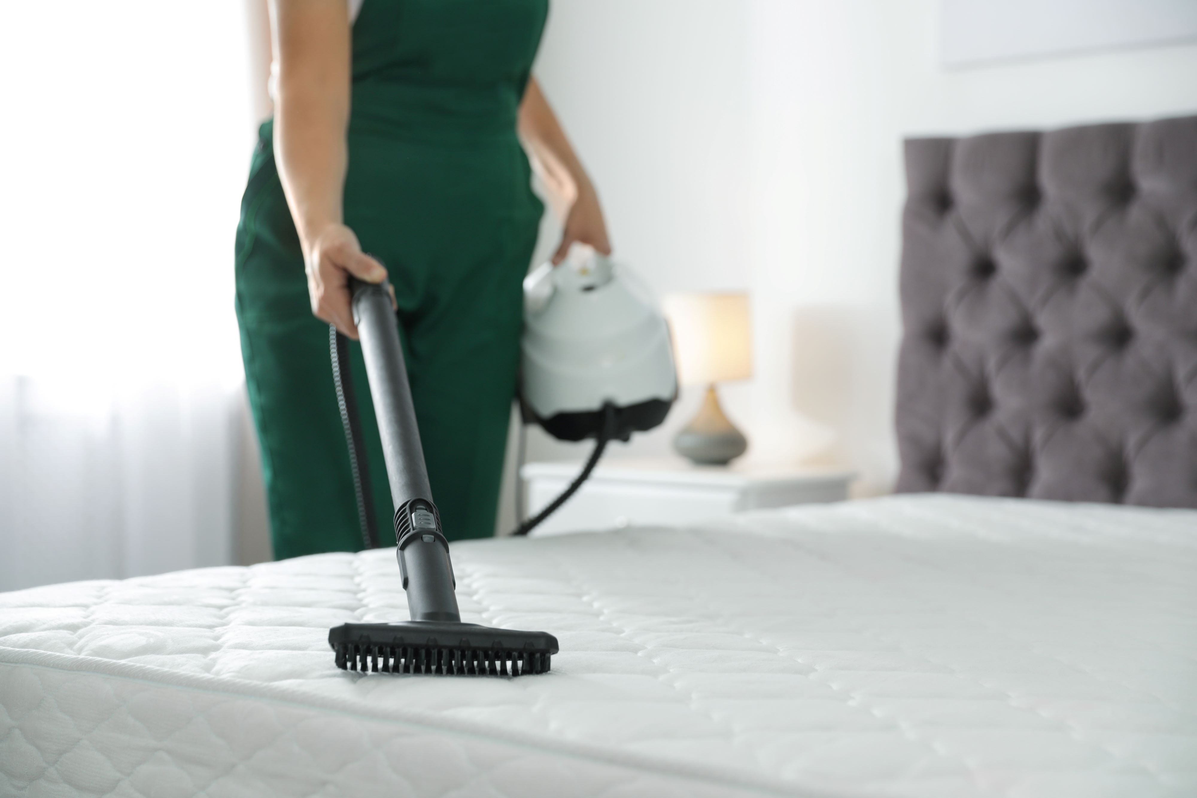 Woman vacuuming a mattress.